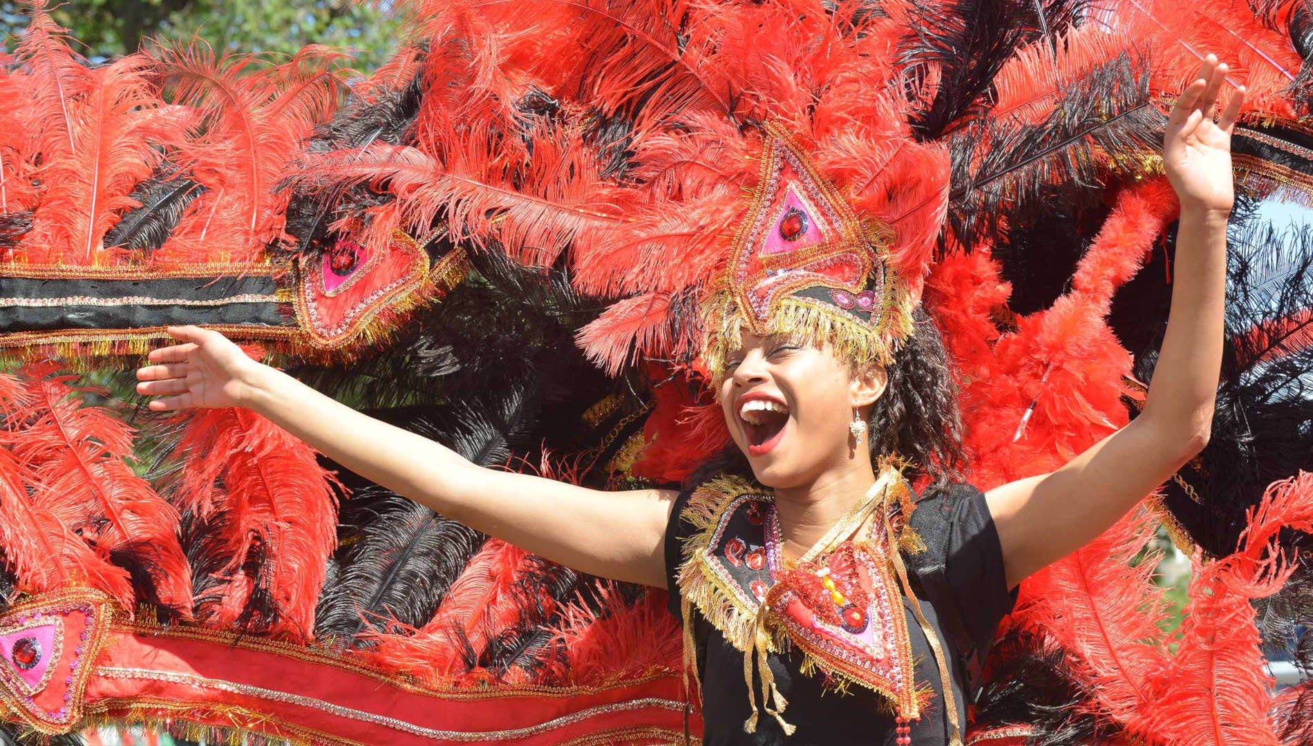 Young person dancing at the carnival wearing a feathered headpiece 
